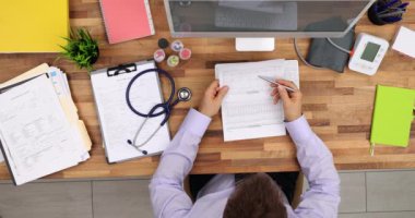 Doctor checkups patient tests result sitting in front of large monitor at workplace. Therapist reads medical records at desk in hospital office upper view