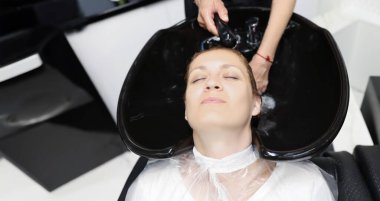 Kadın portresi, güzellik salonunda şampuan ve masajla yıkanırken kendini rahat ve rahat hisseder. Saç için lüks tedavi. Refah kavramı