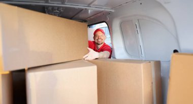 İşteki neşeli adamın portresi adrese teslim edilmesi için kutuları kamyona koydu. Mutlu adam taşınma ve eşyaları taşımana yardım ediyor. Yardımcı kavram