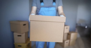 Close-up of worker loading cardboard boxes with owners belongings to new apartment. Guy from delivery service help with relocation. Loader, moving concept clipart