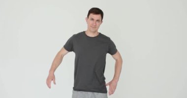 Spor giysili adam beyaz arka planda güçlü kaslar gösteriyor. Brunet erkek atleti vücut geliştirmede fitness başarısını gösteriyor