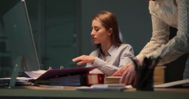 Odaklanmış kadın, ofiste geç saatlere kadar kalan erkek asistanla belgeleri kontrol ediyor. Yorgun meslektaşlarım geceleri önemli projeler üzerinde çalışmaya devam ediyor.