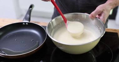 Erkek eller sıcak tavaya dökülen kepçeyle hamur topluyor. Erkek aşçı mutfakta kahvaltıda lezzetli krepler pişirmekle meşgul.