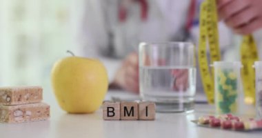 BMI kısaltması hastanede mezurayla doktora karşı. Üniformalı doktor hastaya sağlıklı beslenme özelliklerini açıklıyor