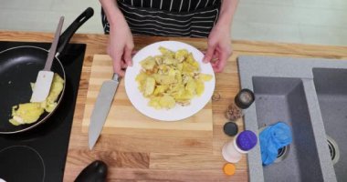 Yemekhanede içi çırpılmış yumurta ve patatesle dolu beyaz tabak var. Şef, modern mutfakta akşam yemeği için sağlıklı yemeğin tadını çıkarmayı teklif ediyor.