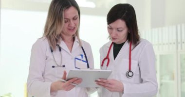 Üniformalı kadın doktorlar hastane ofisinde duran evrakları inceliyor. Kadın sağlık görevlileri klinikte tedavi planıyla anlaştıklarını belirterek başlarını salladı