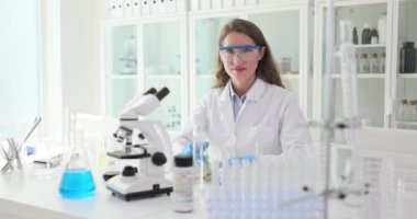 Kadın bilim adamı laboratuarda test tüpü tutuyor. Kadın işçiler bilimsel araştırmalardan tatmin oluyorlar.