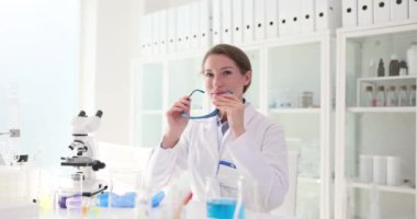 Beyaz cüppeli esmer bilim adamı laboratuardaki iş yerinde koruyucu gözlük takıyor. Kendinden emin genç bayan bilimsel araştırmaya hazırlanıyor.