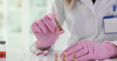Doktor, laboratuvarda tehlikeli bir hastalığa karşı aşıyla cam ampul tutuyor. Tıbbi uzman, bilimsel laboratuardaki hastalar için tedavi hazırlıyor