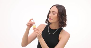 Genç kadın, beyaz arka planda organik yağ kokusu alıyor. Esmer kadın güzellik ve kişisel bakım rutinini kozmetik ürünlerle somutlaştırıyor.