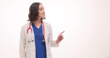 Kendine güvenen kadın doktor beyaz arka planda parmakları ile işaret ediyor. Steteskoplu kadın çocuk doktoru hastanedeki iş arkadaşlarına bilgi veriyor