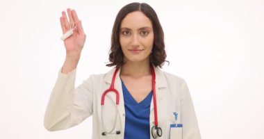 Kadın doktor beyaz arka planda tampon ve hijyenik ped gösteriyor. Doktor, regl akış seviyelerine göre doğru boyutu seçmenin önemini açıklıyor.