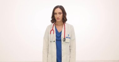 Genç kadın doktor, beyaz arka planda hayal kırıklığı ve zihinsel yorgunluk belirtileri gösteriyor. Esmer bir doktorun gözleri yorgunluğu yansıtır.