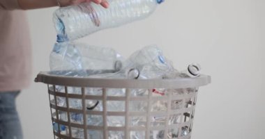 Kadın eli, beyaz arka planda plastik şişeyi geri dönüşüm kutusuna atıyor. Farkındalık kadını çevreyi kolay adımlarla korur.