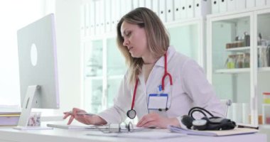 Odaklanmış kadın doktor hastanedeki işyerindeki klavye daktilo raporunda tuşlara basıyor. Sarışın kadın sıhhiyeci, veri girdisiyle iş sürecine girdi