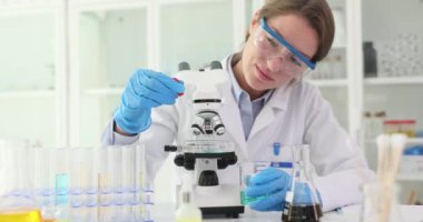 Kadın kimyager numuneyi laboratuarda pipete mikroskop altında yerleştiriyor. Profesyonel teknisyen bilimsel araştırma ve analiz yürütüyor.