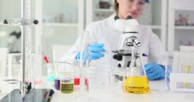 Kadın asistan, laboratuardaki mikroskoba cam parçaları yerleştiriyor. Biyolog cam eşyalar ve laboratuvar aletleriyle madde örneklerini araştırıyor.