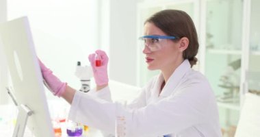 Konsantre esmer teknisyen laboratuvar ortamında bilgisayar ekranına dokunuyor. Kadın eczacı sanal tabana deney verileri yerleştiriyor