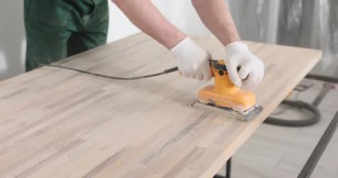 Marangoz kumları ahşap masa tezgahı ve elektrikli cilalama makinesi. Tamirci inşaat alanında tahta ve manüel aletlerle çalışıyor.