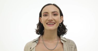 Neşeli genç bir kadın stüdyoda beyaz arka planda fotoğraf için poz veriyor. Hoş gülüşü olan mutlu esmer kadın olumlu duygular gösteriyor.