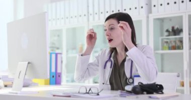 Kadın hekim inançsızlıkla bilgisayar ekranına bakıyor. Şaşırmış ifadeli bir doktor masada oturur ve beklenmedik muayene sonuçlarını inceler.