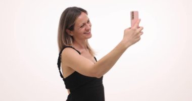 Gülümseyen kadın beyaz arka planda mükemmel selfie çekmek için modern akıllı telefonu kullanıyor. Kadın, telefondaki kamera ayarlarını ideal fotoğraf çekmek için ayarlar