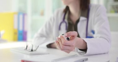 Kadın doktor gerilimi azaltmak için stres topu sıkar. Doktorlar ofiste masa başında oturur ve yoğun ağır çekimde stresle başa çıkmaya çalışırlar.