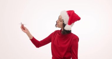 Noel Baba şapkalı mutlu kadın beyaz arka planda seyahat hayali kuran oyuncak uçakla oynuyor. Çekici bayan yeni yılda tatile çıkmak istiyor.