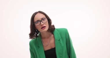 Kafası karışmış bir kadın gözlüğünü çıkarır ve beyaz arka planda şaşkınlık yaşar. Yeşil ceketli esmer kadın hayret ediyor.