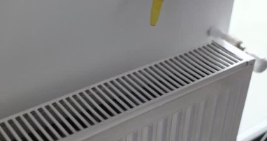 Elektrikli süpürgeyi ısıtma bataryasının üstünde tutan kişi. Profesyonel temizlik hizmeti, ulaşılması zor yerlerde temizlik hizmeti sunuyor