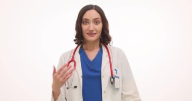 Kadın terapist beyaz arka planda içten şükranlarını sunuyor. Esmer doktor jestleri klinikte samimiyet ve takdiri ifade eder.