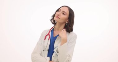 Beyaz arka planda olumlu ifadeli düşünceli bir kadın doktor. Neşeli kadın tıbbi uzman hayalleri sağlık merkezinde tek başına duruyor.