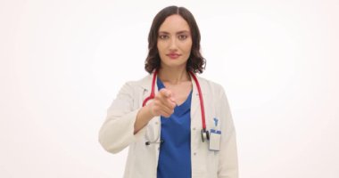 Kadın doktor, beyaz arka planda Call Me jestini gösteren parmağıyla işaret ediyor. Üniformalı neşeli kadın doktor meslektaşıyla iletişim kuruyor.