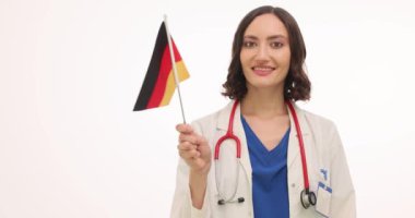 Üniformalı kadın doktor mutlu bir şekilde beyaz Alman bayrağı sallıyor. Steteskoplu mutlu kadın terapist, işbirliğini kutlayan ulusal bir sembol taşıyor
