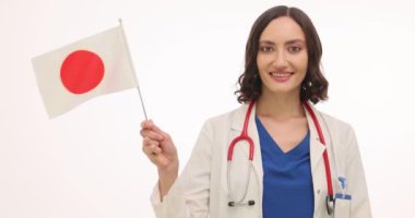 Üniformalı kadın doktor beyaz arka planda Japon bayrağı sallıyor. Steteskoplu gülümseyen kadın doktor modern hastanede çalışıyor.