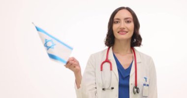 Üniformalı kadın doktor beyaz arka planda İsrail bayrağı sallıyor. Steteskopla gülümseyen kadın sıhhiyeci İsrail sağlık ekibini karşıladı