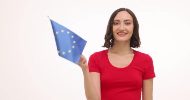 Gülümseyen kadın beyaz arka planda Avrupa Birliği bayrağı sallıyor. Genç bir kadın, tatili kutlayan ve seyahat etmeyi hayal eden mutluluk ve gurur yayar.