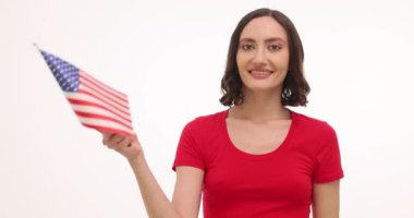 Kırmızı tişörtlü esmer kadın beyaz arka planda minyatür Amerikan bayrağı sallıyor. Kadın vatansever ulusal bayramı kutlarken neşe saçıyor