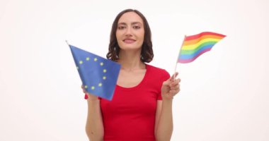 Kırmızılı kadın, beyaz arka planda Avrupa Birliği ve LGBT gökkuşağı bayrakları sallıyor. Genç eylemci demokrasi ve özgürlük değerlerini destekliyor