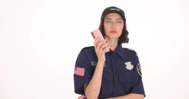 Lacivert üniformalı kadın polis, beyaz arka planda akıllı telefon sohbeti yapıyor. Esmer subay teneffüste tek başına hücrede konuşuyor.