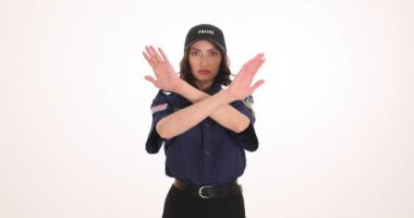 Kadın polis beyaz arka planda çapraz kollu dur işareti gösteriyor. Ciddi kadın memurlar suç mahallinde yasak olduğunu gösteriyor.