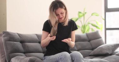 Üzgün kadın evdeki yumuşak koltukta otururken cüzdanından bozuk para döküyor. Hayal kırıklığına uğramış sarışın kadın, nakit akışını kontrol ederken finansal sorunlar yaşıyor.