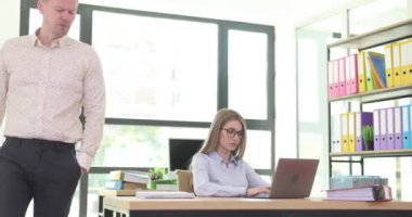 Erkek patron modern şirket ofisindeki kadın asistana iş görevlerini açıklıyor. Bayan tipler dizüstü bilgisayardan rapor veriyor. Odada dolaşan işadamlarının talimatlarını dinliyorlar.