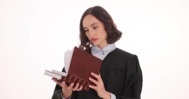Önlüklü kadın avukat beyaz arka plan ile ilgili hukuk kitabını açıyor. Odaklanmış esmer, hukuk alanında profesyonelliği ve adanmışlığı temsil ediyor.