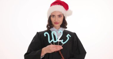 Önlüklü ve Noel Baba şapkalı kadın yargıç beyaz arka planda 2025 'in rakamlarını taşıyor. Mutlu kadın mahkeme salonunda tokmak tutarak bayramı kutluyor.