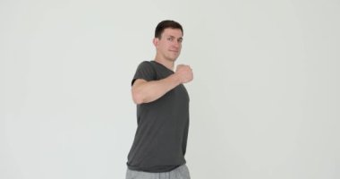 Spor kıyafeti giymiş erkek antrenör göğsüne beyaz arka planda neşeyle vuruyor. Pozitif erkek antrenörü, spor becerilerini yavaş çekim artırmak için seyirciyi kendine çekiyor