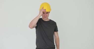 İnşaat işçisi beyaz arka plana sarı bir şapka takıyor. İnşaatçı inşaat alanında ağır çekimde başlığı korumak için kask kullanıyor.