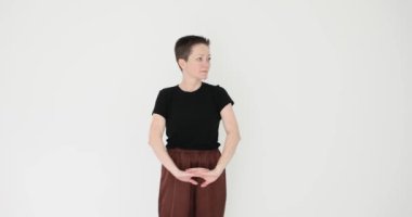 Kadın kollarını ve bileklerini beyaz arka planda geriyor. Kadın modeli, birleşik ellerin zarif hareketlerini gösteriyor. Yavaş çekimde dans provası yapıyorlar.