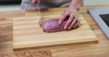 Kadın, patlıcanın yarısını keskin bir bıçakla tahta kesme tahtasıyla kesiyor. Ev hanımı organik sağlıklı malzemelerle yavaş çekimde yemek pişirir.