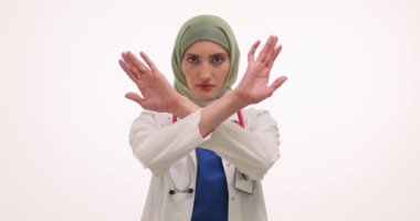Başörtüsü takan kadın doktor, beyaz arka planda elleri olan yasak hareketi gösteriyor. Steteskoplu Müslüman kadın doktor anlaşmazlık dile getirdi